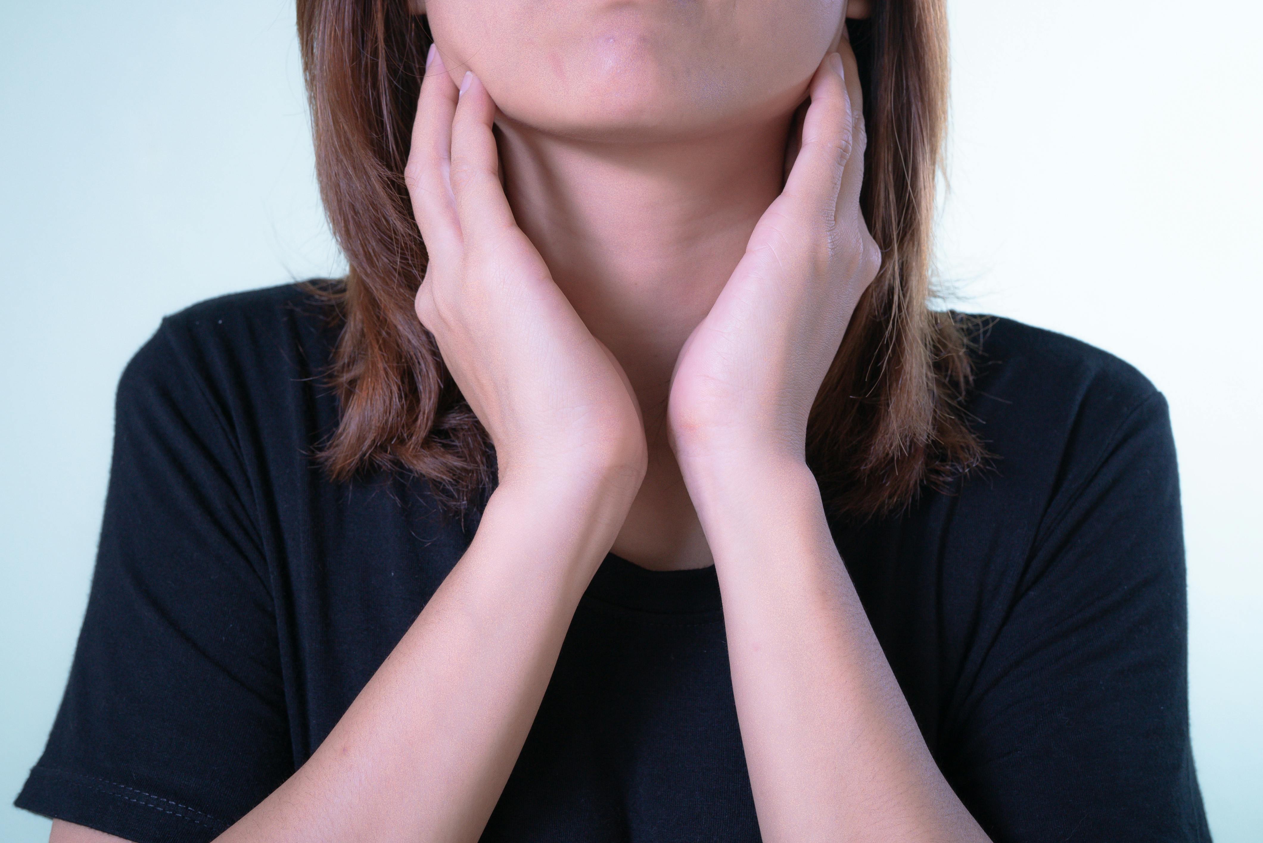 Woman touching her throat while feeling soreness